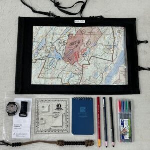 Land Nav Kit: Map case, compass, notepad, pens, and navigation tools laid out on a table.